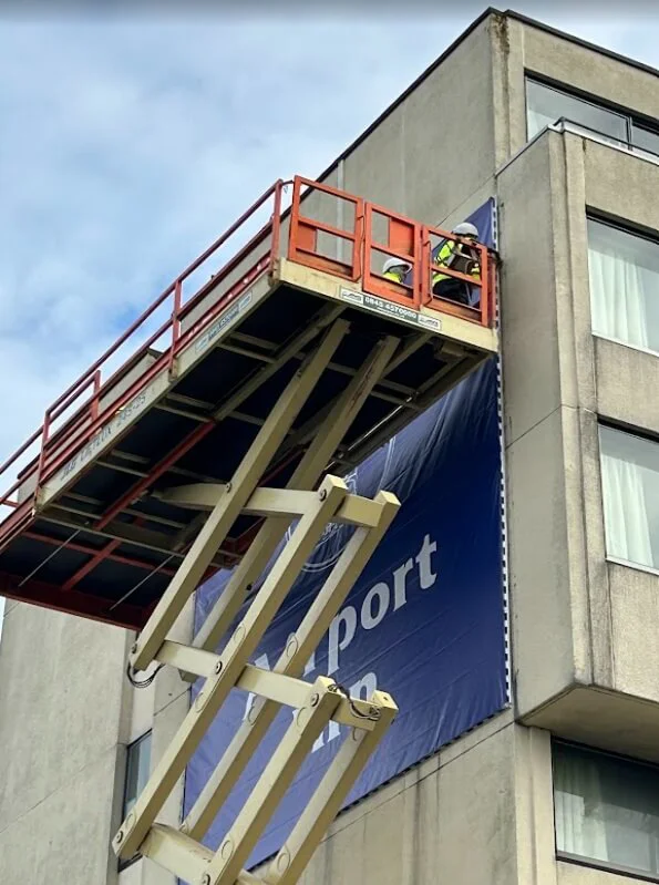 An image of an "Airport Inn" exterior building sign being installed.